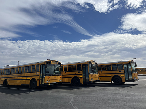 Three school busses parked in the school parking lot