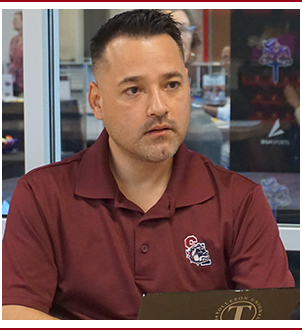 Tolleson Union employee in maroon polo shirt sitting at desk