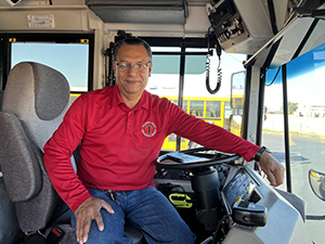 Group of transportation staff members pose together in front of a school bus